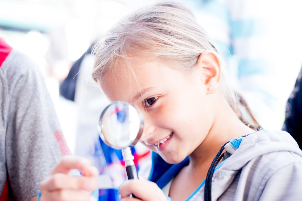 Girl looks through magnifying glass