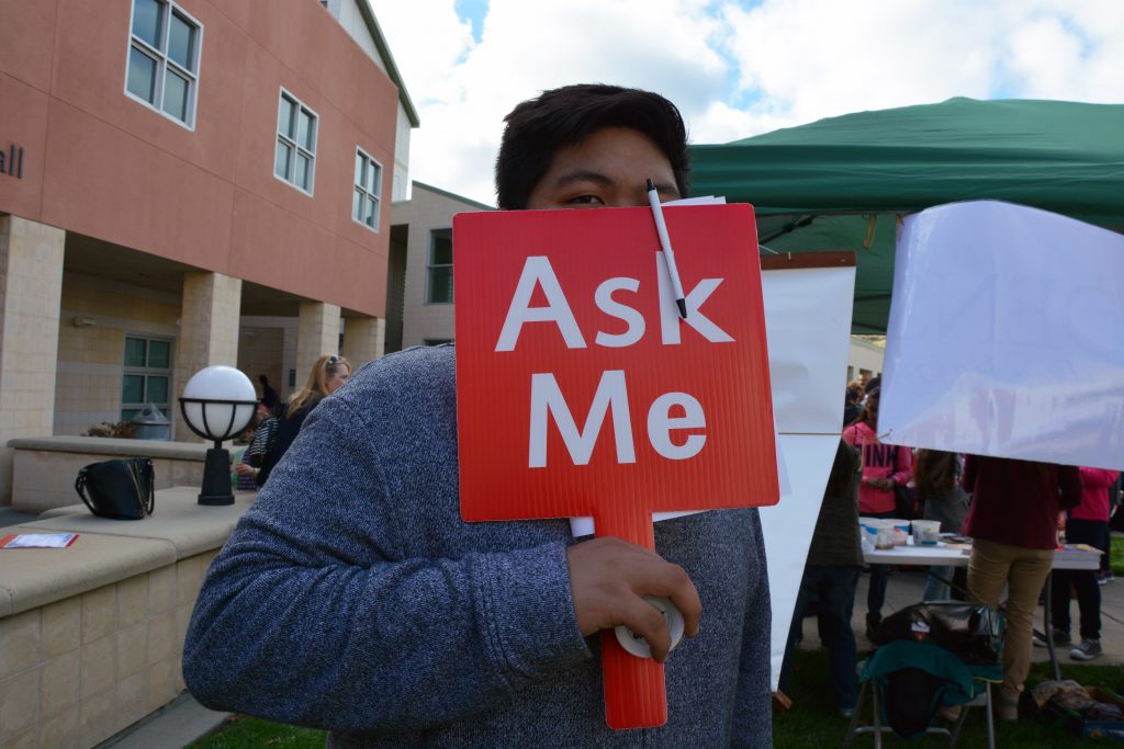 A volunteer holds up an Ask Me sign during a Festival event.