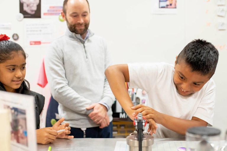 Boy excitedly using button maker machine in UCSF's Makers Lab