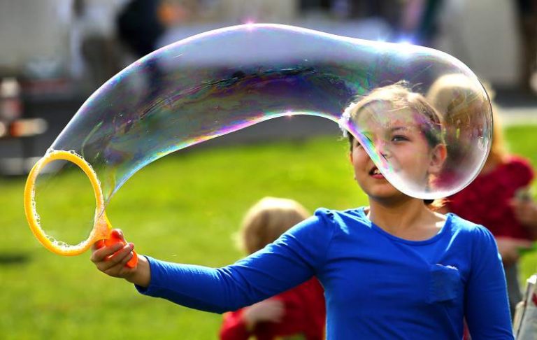 A girl makes a large bubble.