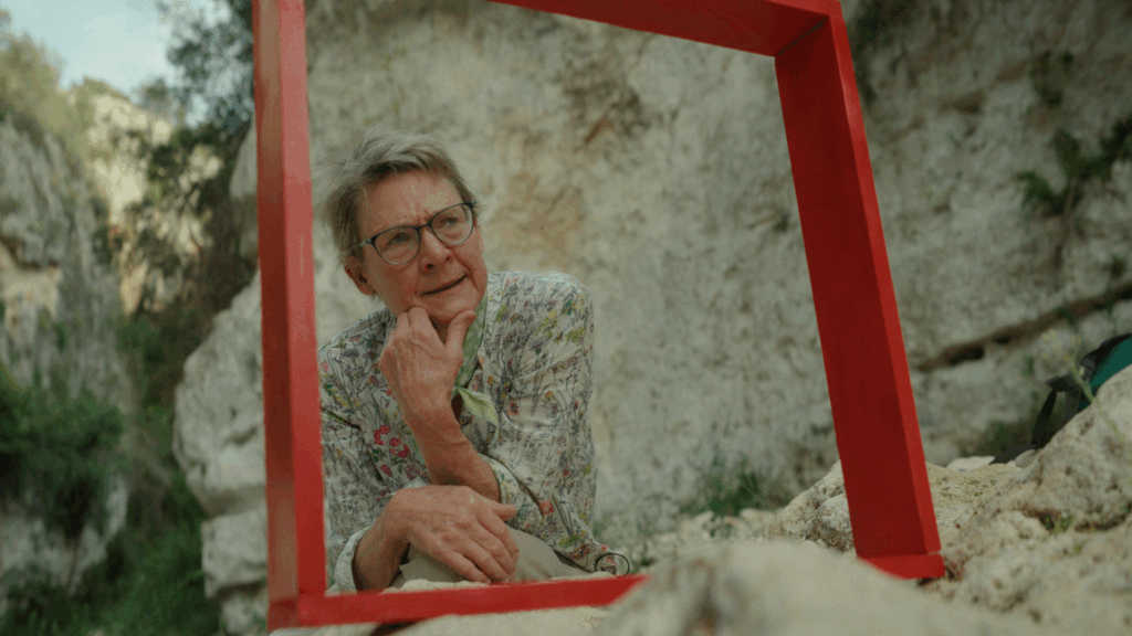 Hidden Worlds film still image: older woman observing her surroundings through a bright red square